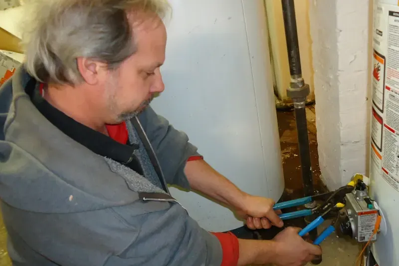 Plumber tightening a water fitting with two wrenches