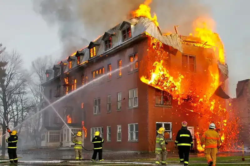 Firefighters spraying water on a burning brick building